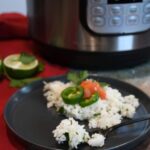 Jasmine rice with fresh cilantro and lime that has been made in the Instant Pot on a plate with a fork.