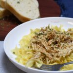 A bowl full of crock pot Mississippi chicken over egg noodles.