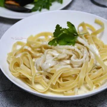 A close up of a bowl that has noodles that is topped with homemade alfredo sauce with heavy cream.