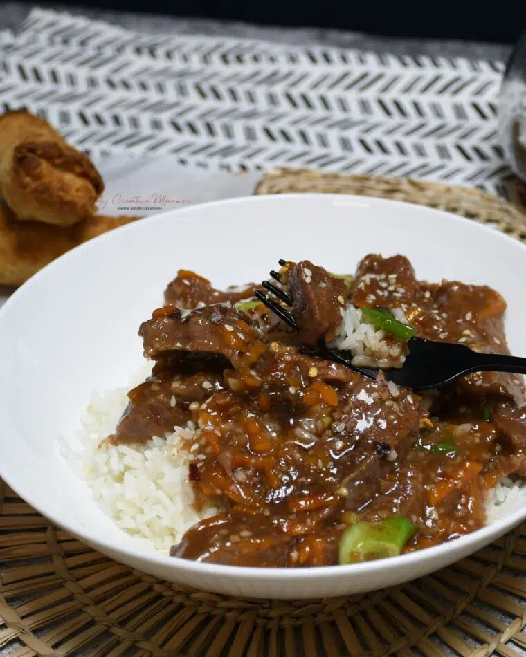 An image of crock pot Mongolian beef in a bowl with a fork.