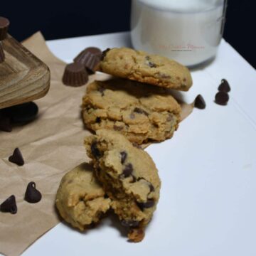 A close up of peanut butter cup cookies with Reese's on a wood platter.