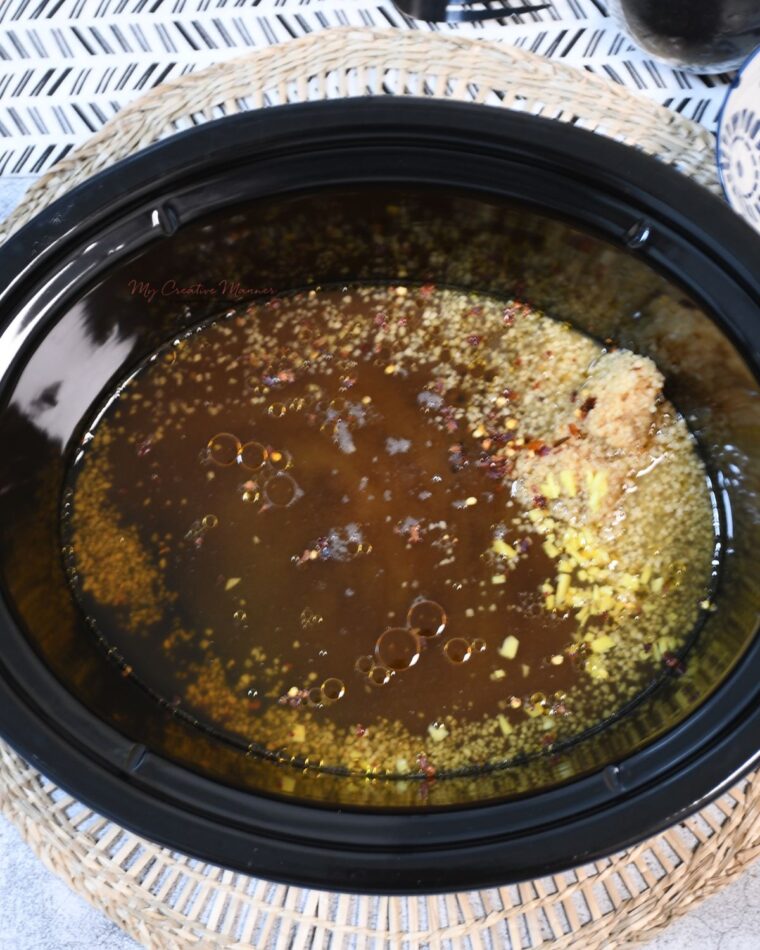 A crockpot that is filled with the sauce ingredients for Mongolian beef.