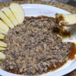 A dish of caramel apple dip with apples.
