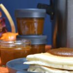 Pancakes with crockpot pumpkin butter on top of them. And with mason jars filled with more behind the pancakes.