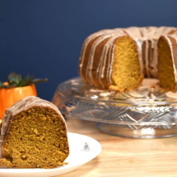 Pumpkin cake on a platter with a slice of the bundt cake on a plate.