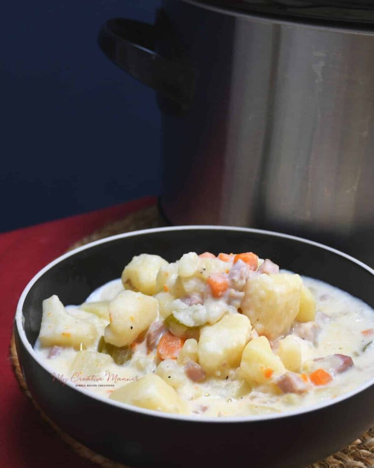A bowl of hearty crockpot potato and ham soup in a bowl.