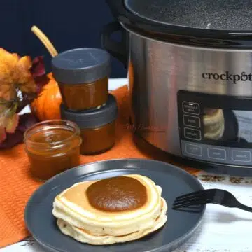 Overhead shot of pancakes with pumpkin butter on them. With a crockpot and and canning jars with more fruit butter in them.