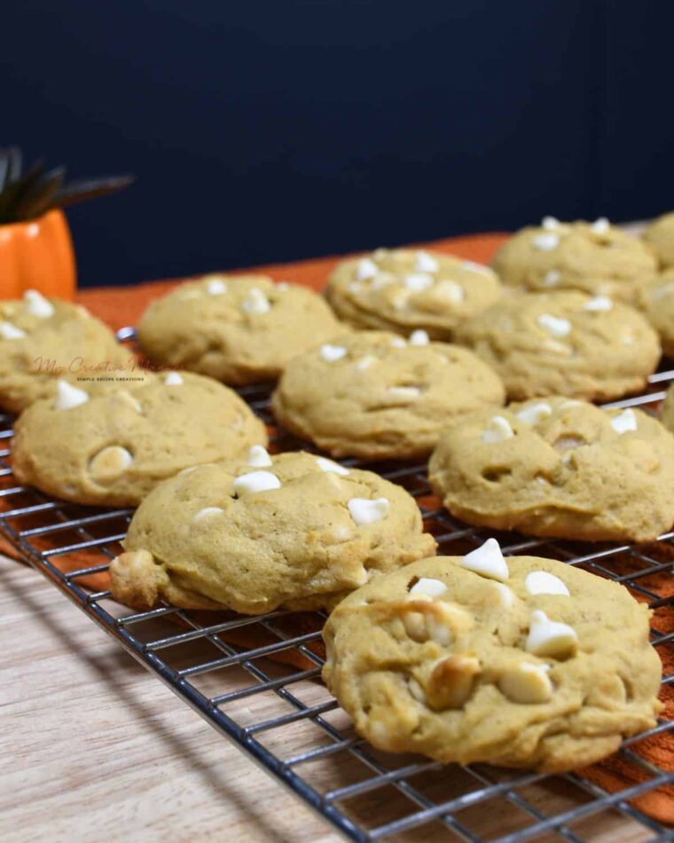 Pumpkin spice cookies with white chocolate chips on a cooling rack.