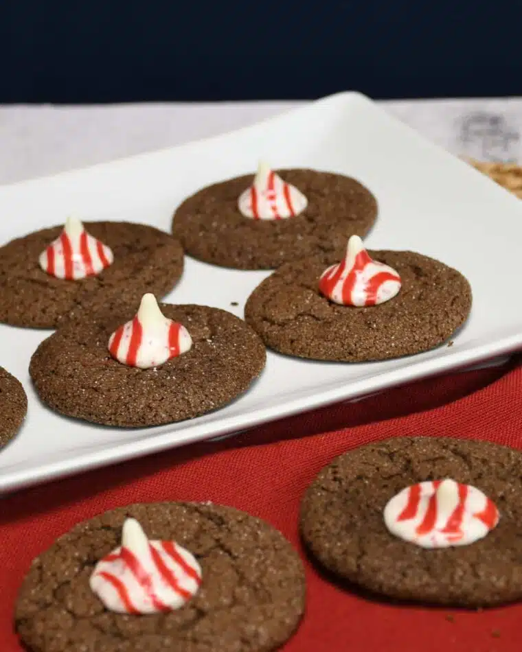 A plate with fresh baked Christmas cookies that have peppermint kisses in the center of each cookie.