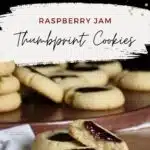 The words raspberry jam thumbprint cookies over two cookies on is broke in half.