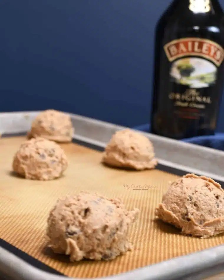 A raw dough ball of Bailey's Irish cream chocolate chip cookies on a baking sheet pan.