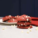 A stack of rev velvet cake mix cookies with more on a white plate.