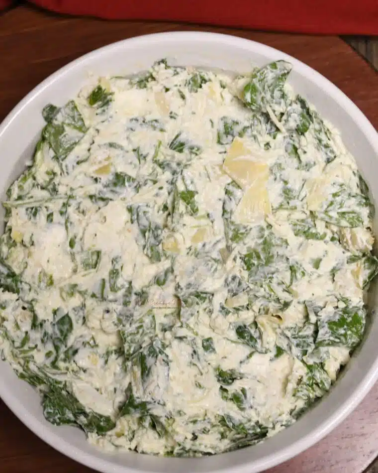 A baking dish filled unbaked crab spinach artichoke dip recipe.