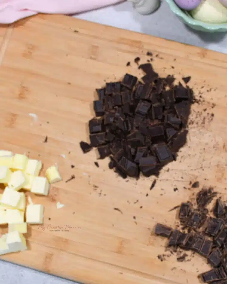 Baking chocolate and unsalted butter that have been chopped and cubed on a cutting board.