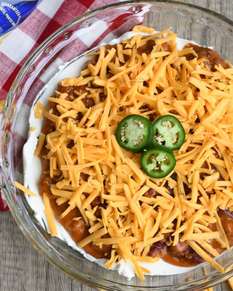 Overhead image of a pie dish filled with unbaked ingredients to make chili cheese dip.