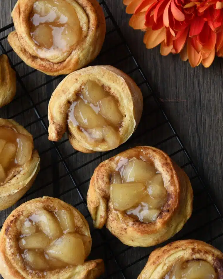 Overhead sho of baked cinnamon roll apple pie cups without cream cheese frosting.
