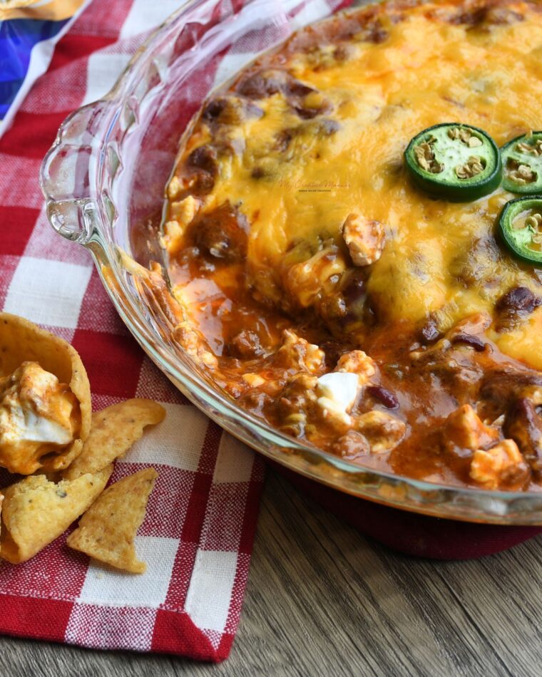 Oven baked chili and cheese dip recipe that is made with three ingredients in a pie dish.