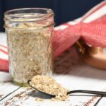 A spoon that has some of the simple homemade onion mix recipe on it with more in a jar.