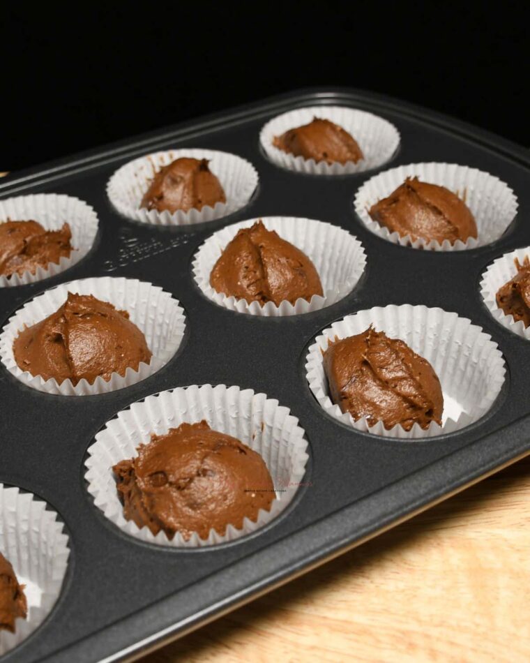 A muffin pan with the batter for pumpkin chocolate muffins.