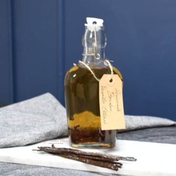 A bottle of homemade bourbon vanilla extract with vanilla bean in front of it.