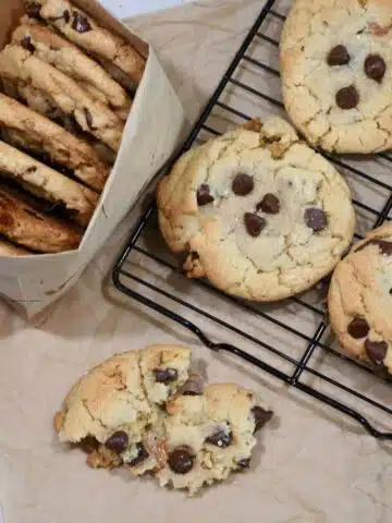 Overhead image of salted caramel chocolate chip cookies on a wire rack and some in a paper bag.