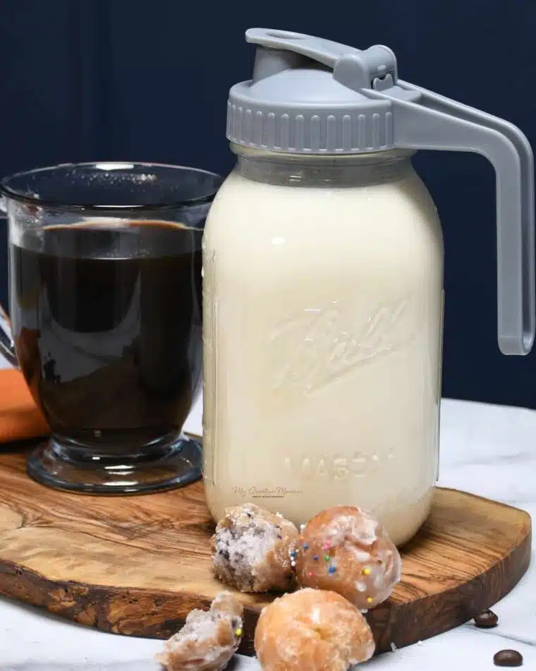A close up of homemade vanilla coffee creamer with a cup of coffee next to it.