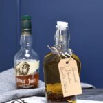 A bottle with homemade vanilla extract and a bottle of bourbon behind it.