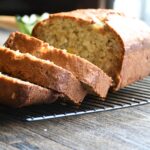 The front of a banana bread loaf with crushed pineapple and shredded coconut that has been sliced.