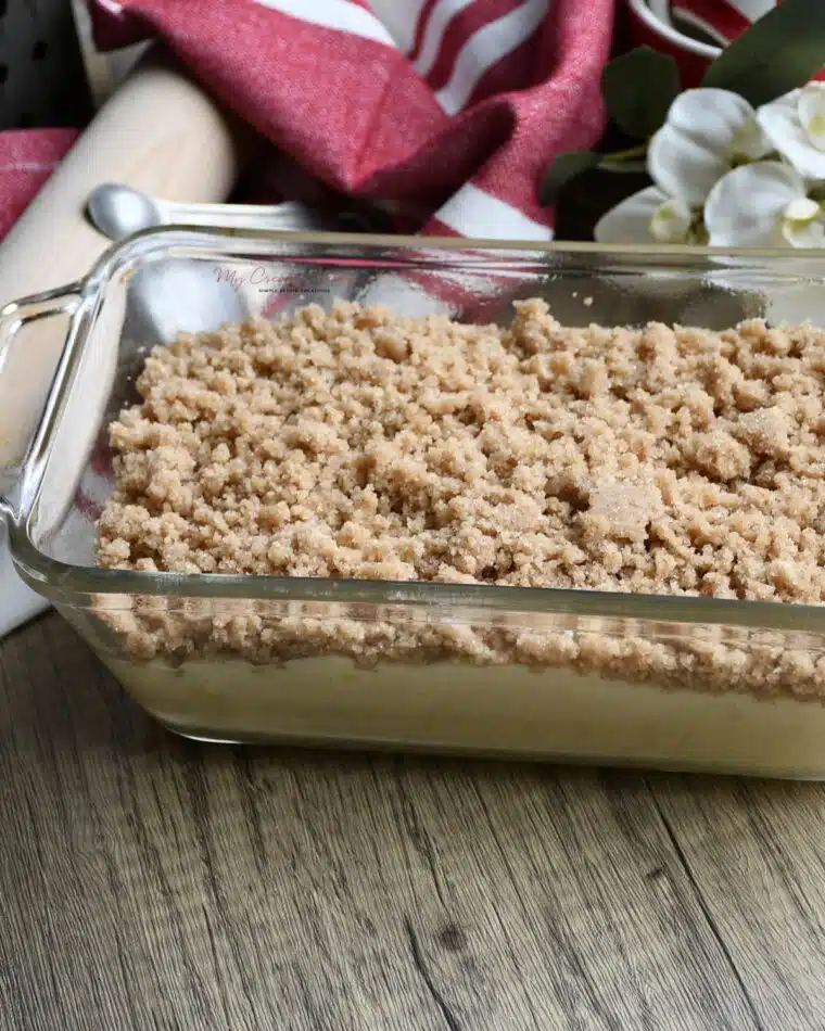 A loaf pan that is filled with the banana bread batter and topped with the streusel topping.