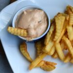 A closeup over head image of a dish with the chipotle dip and a French fry in it.