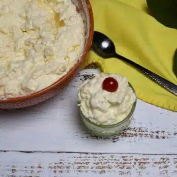 Overhead image of two dishes that have the pineapple fluff salad in it. The smaller dish has a cherry on top.