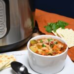 Close up of a bowl of easy Instant Pot Minestrone soup with crackers next to the bowl on a plate.