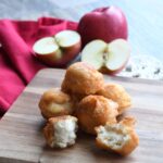 A close up of the 2 ingredient apple donuts stacked on a wood plate.