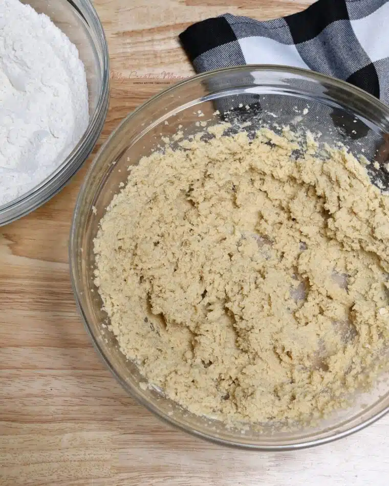 A bowl with creamed butter and sugar with another bowl with sifted flour in it for these Chocolate Chip Oreo cookies.