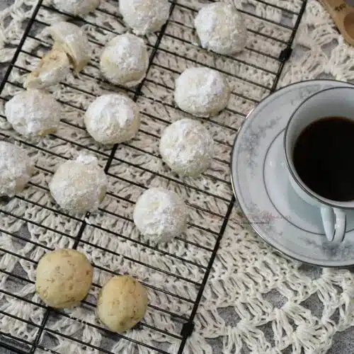 Overhead image of the cookies on a cooling rack for this butterball cookie recipe with a tea cup next to them.