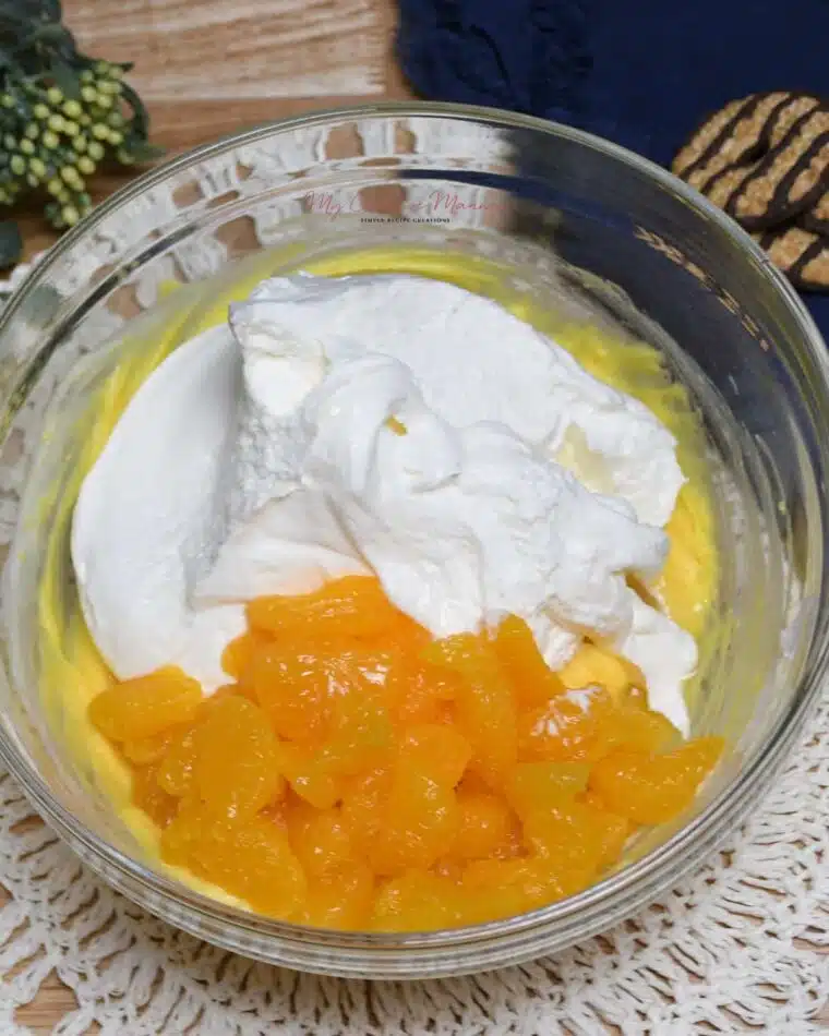 Overhead image of a bowl that has vanilla instant pudding, Mandarin oranges, and cool whip in it.