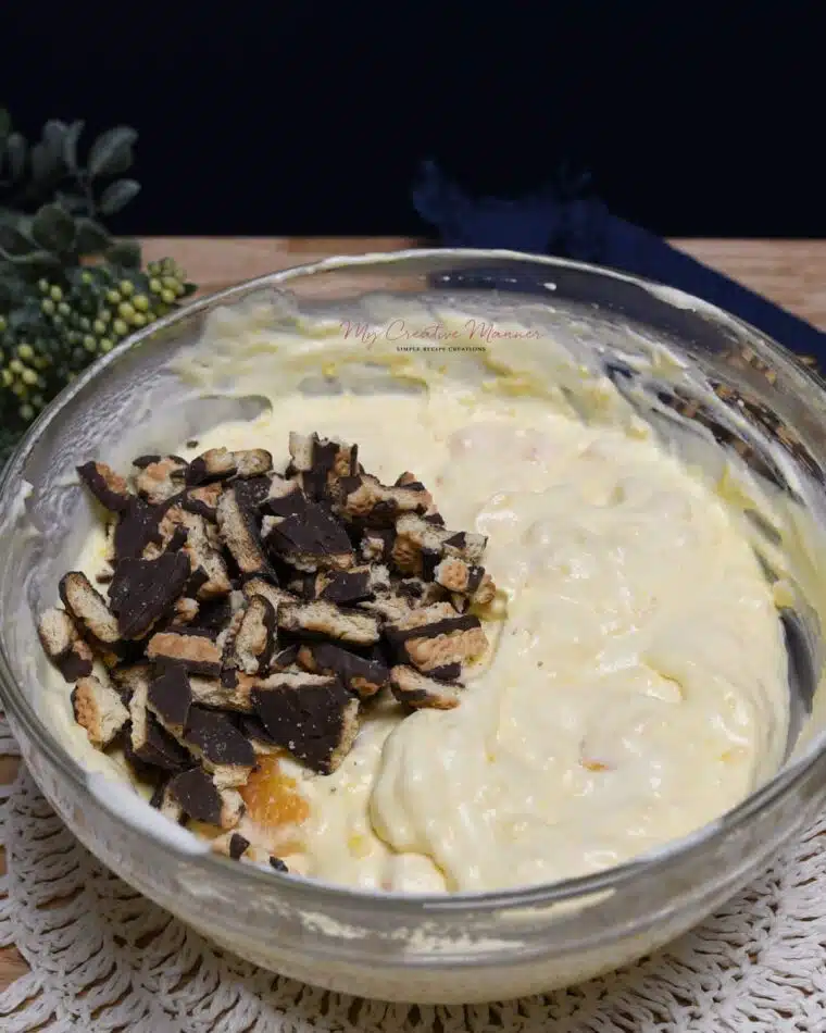 Overhead image of fudge stripe cookies being added into a bowl of fluff salad.