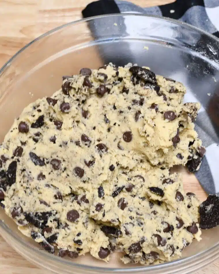 A bowl with the cookie dough for chocolate chip cookies with Oreos in it.