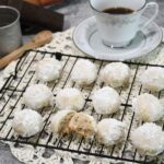 A close up of butterball cookies on a cooling rack with one cut in half.