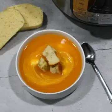 Overhead image of the butternut squash soup with croutons in a bowl and an Instant Pot next to the bowl.