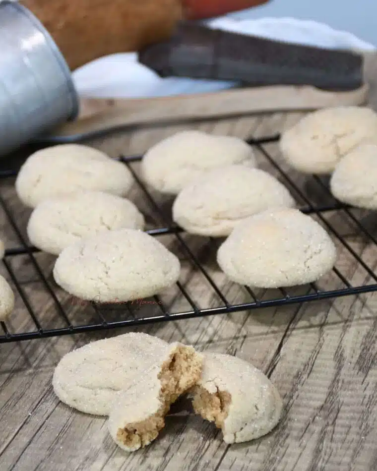 A cooling rack with the cookies on it and a gingerbread cookie in front that has been split open.