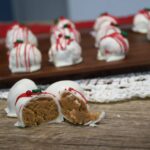 Close up a a snickerdoodle ball in half with more on a tray behind it.