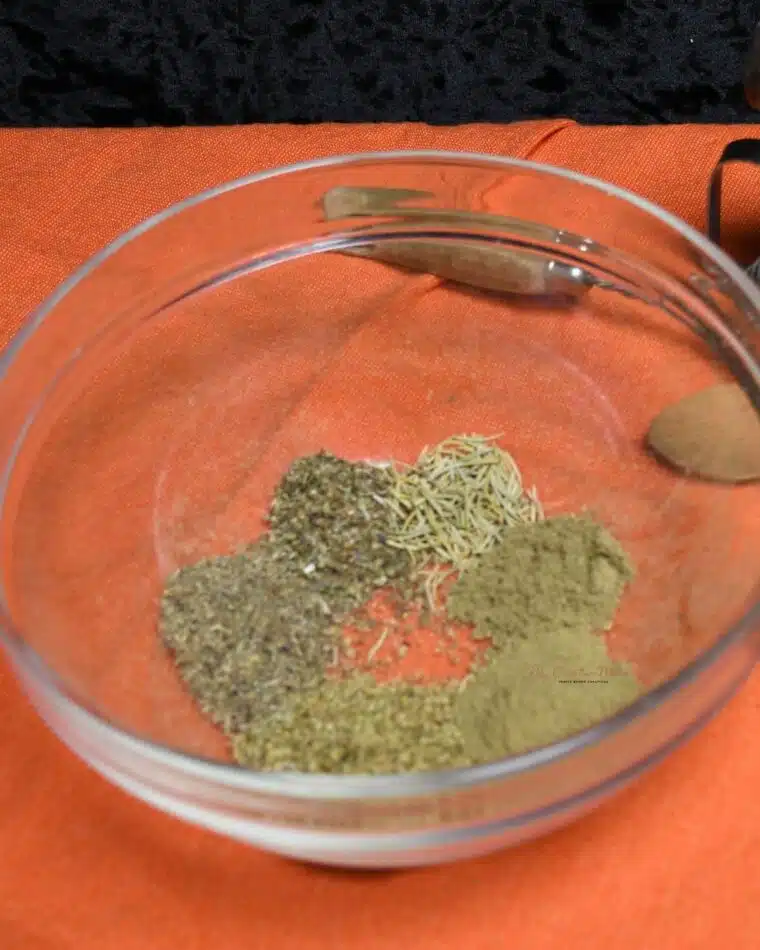 Front view of a bowl filled with the ingredients to make homemade Italian seasoning mix.