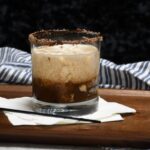 Front of a glass that is full of a chocolate white Russian cocktail.