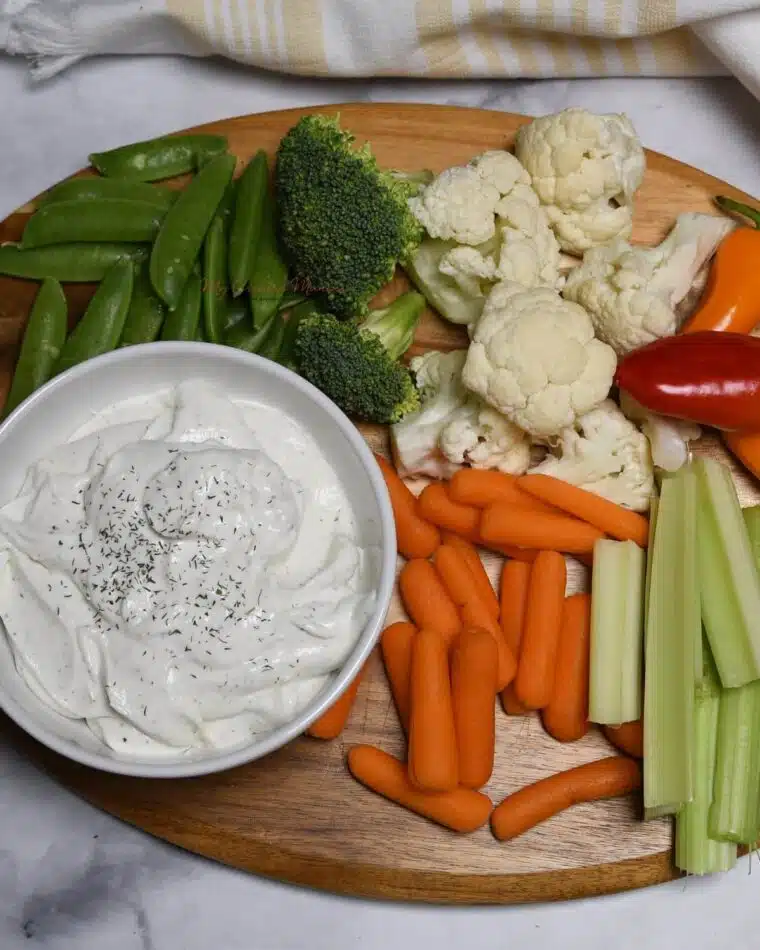 Overhead view of a platter of veggies with a bowl of the ranch cottage cheese dip.