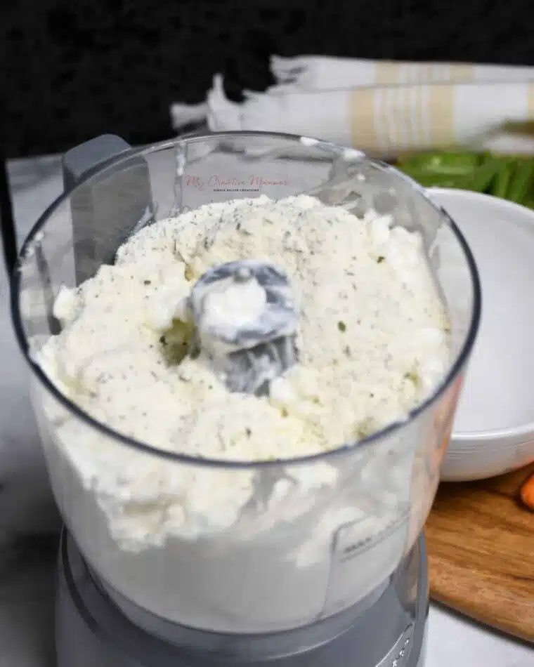 A mini food processor with cottage cheese and ranch seasoning mix in it.
