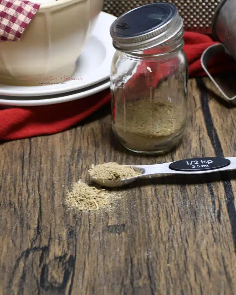 A mason jar with homemade poultry seasoning with more in a spoon.