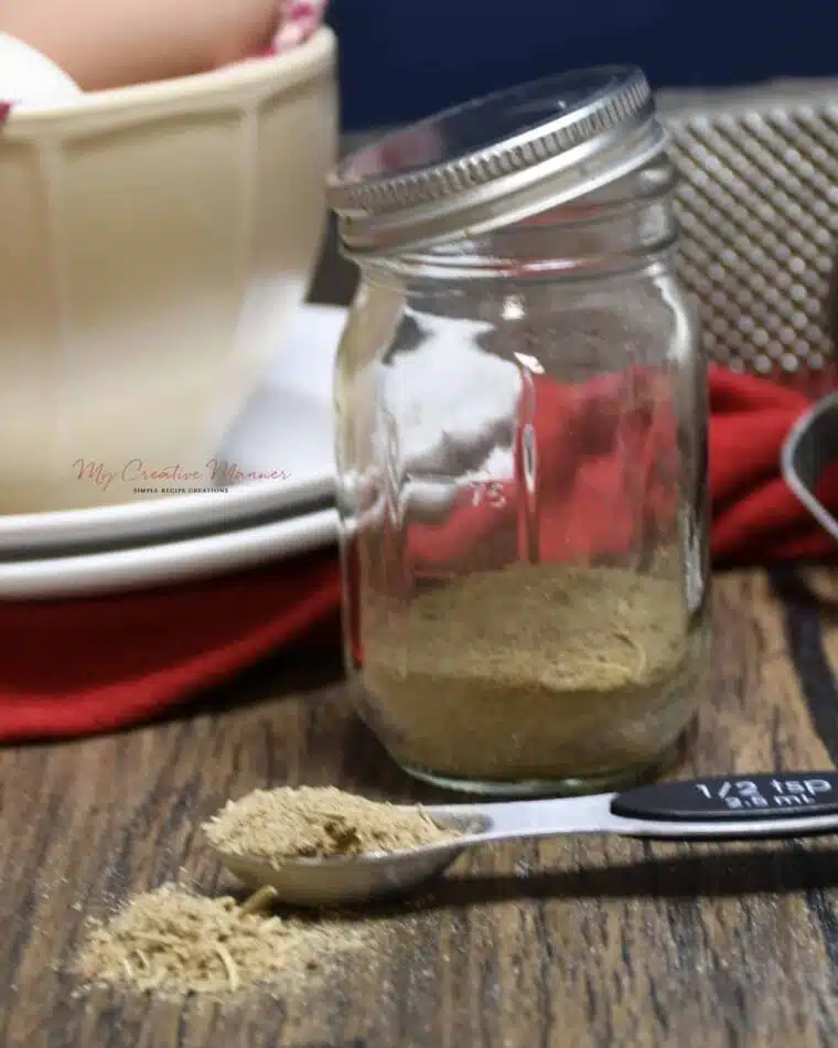 A measuring spoon filled with the homemade blend and more of the chicken seasoning in a mason jar.