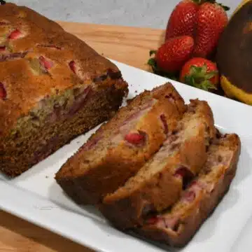 A loaf of strawberry banana bread that has been slice that is on a platter.