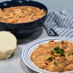 A plate that has this delicious creamy beef and shells recipe on it with more in a bowl behind the plate.